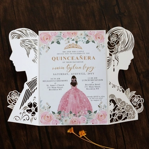 Macro shot of laser-cut Quinceañera invitation with floral lace and silhouettes on wood