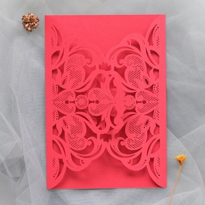 Macro detail of laser-cut red lace invitation card with intricate scrollwork patterns