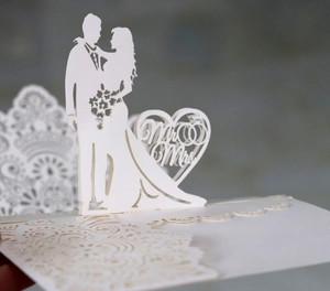 Detail of laser-cut ivory 3D wedding card featuring Mr & Mrs silhouette and lace patterns