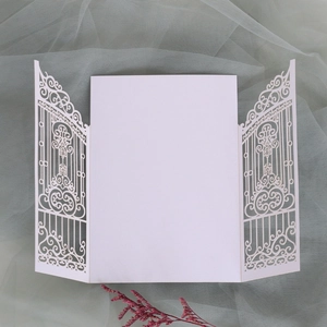 Close-up of white laser-cut gate design wedding invitation with elegant hollow patterns