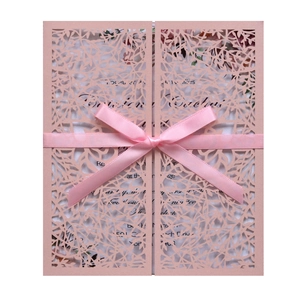 Macro shot of pink laser-cut lace wedding invitation with a silk ribbon bow detail