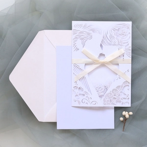 Macro detail of laser-cut rose and couple silhouette on white wedding invitation