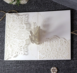 Detail view of laser-cut ivory wedding invitation featuring an elegant lace hollow pattern