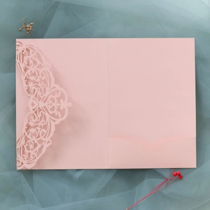 Detail of laser cut lace floral hollow pattern on pink wedding invitation pocket