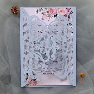 Detail of laser-cut light blue wedding invitation with floral inner card and lace pattern
