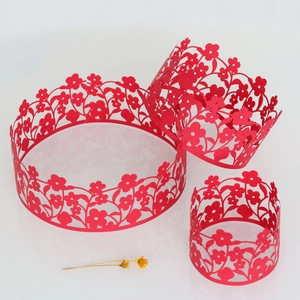 Macro detail of red laser-cut paper cake collars with intricate hollow flower patterns