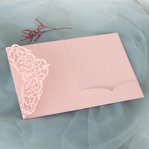 Detail of pink laser-cut wedding invitation cover with intricate floral pattern