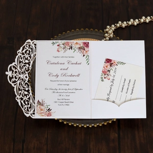 Macro view of laser-cut wedding invitation shell with elegant floral insert cards