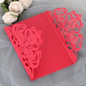 Detail of red laser-cut wedding invitation featuring intricate floral lace patterns