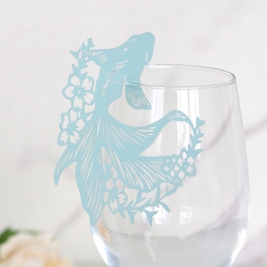 Macro view of light blue fish-shaped laser-cut paper wine glass card decoration