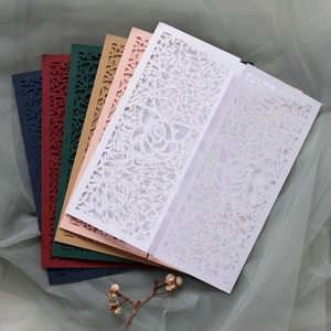 Intricate laser-cut floral wedding invitation covers in multiple elegant colors
