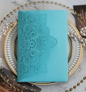 Close-up of laser-cut tiffany blue wedding invitation with intricate mandala floral pattern