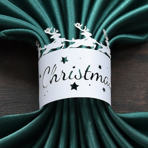 Close-up of a white laser-cut reindeer paper napkin ring featuring a Christmas design