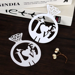 Intricate laser-cut white paper rings with LOVE heart design for wedding wine glass decor