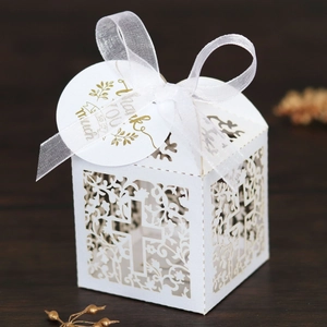 Macro view of white laser-cut cross favor box with thank you tag and white ribbon