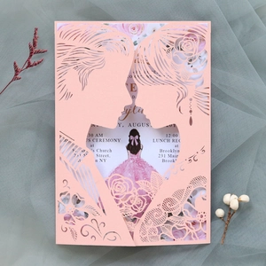 Close-up of pink laser-cut wedding invitation with couple silhouette and floral lace details
