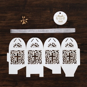 Detail of laser-cut wedding favor box with cross pattern and thank you tag on wood