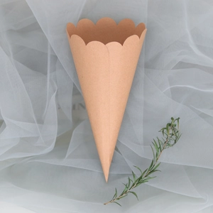 Close-up of brown kraft paper confetti cone with scalloped edges on white tulle fabric
