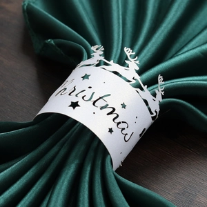 Macro shot of white cutout paper napkin ring with Christmas reindeer and star patterns