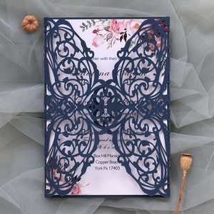Detail of laser-cut navy blue butterfly wedding invitation set on soft mesh background