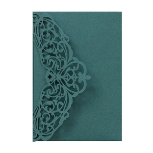 Detail of laser-cut filigree floral and heart patterns on dark green wedding card