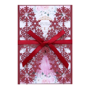 Detail of burgundy laser-cut snowflake invitation with a satin ribbon and floral insert