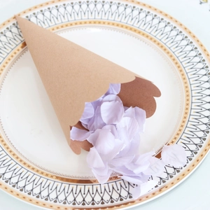 Close-up of brown kraft paper flower cone with lavender petals on a decorative porcelain plate
