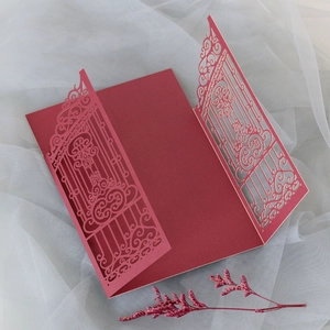 Detail of red laser-cut wedding invitation with elegant gate pattern and dried flower decor