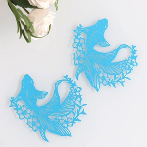 Detail of bright blue laser-cut fish-shaped paper cards with intricate floral patterns