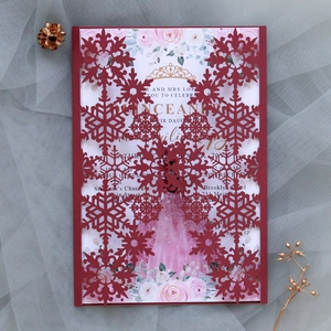Detail of red laser-cut snowflake invitation card with floral insert and gold accents