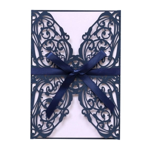 Detail of navy blue laser-cut butterfly invitation card with a satin ribbon bow tie