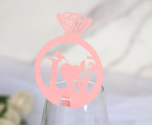 Close-up of a pink laser-cut diamond ring wine glass card with LOVE bird pattern