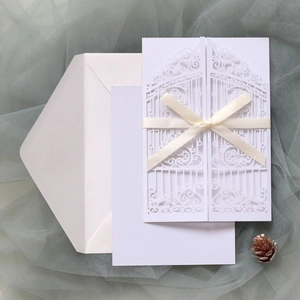 Macro detail of laser-cut wedding invitation gate with elegant cream ribbon bow