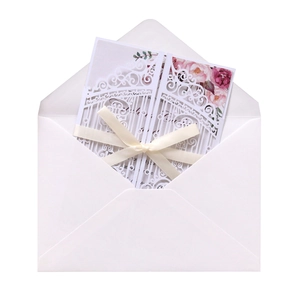 Detail of laser-cut wedding invitation with white floral gatefold and pink rose insert