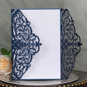 Detail of laser cut navy blue wedding invitation with intricate vine hollow-out patterns