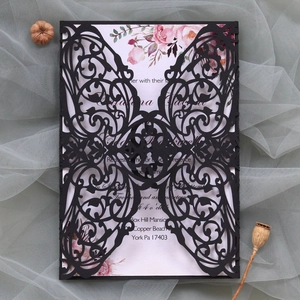 Macro detail of laser-cut butterfly wedding invitation with floral printed inner card