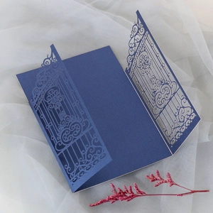 Macro shot of laser-cut navy blue wedding invitation with intricate gate patterns