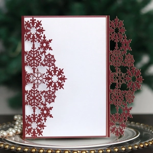 Macro shot of dark red laser-cut snowflake invitation card with white insert and pearl decor