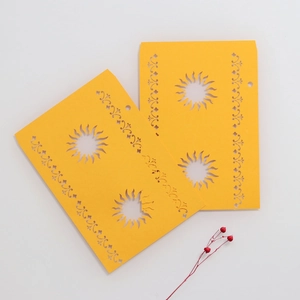 Macro detail of laser-cut sun pattern on yellow cardstock for party lanterns