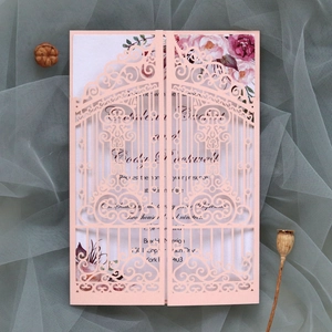 Detail of pink laser-cut wedding invitation featuring gates and floral inner card