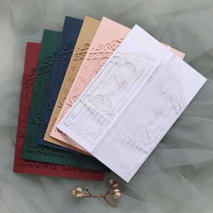 Laser-cut European wedding invitations in multiple colors displayed on soft fabric