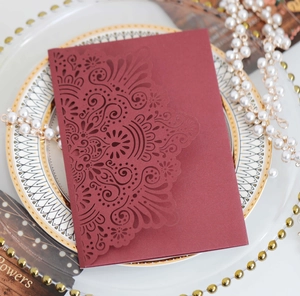 Macro detail of laser-cut burgundy wedding invitation with intricate mandala patterns