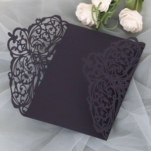 Detail of laser-cut black invitation sleeve with intricate floral patterns on mesh fabric