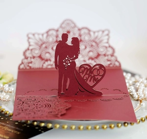Macro detail of laser-cut red wedding card featuring a romantic 3D bride and groom silhouette