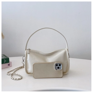 Detail of off-white mini pillow bag with silver chain strap and phone for size comparison