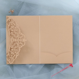 Macro detail of laser-cut lace pattern on deep red pearlescent paper invitation
