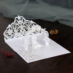 Detailed macro view of laser-cut pearl white 3D wedding card on wooden background