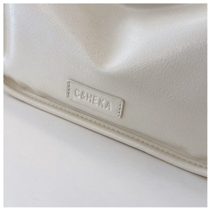 Close-up of the beige textured leather surface and precise stitching on the mini bag