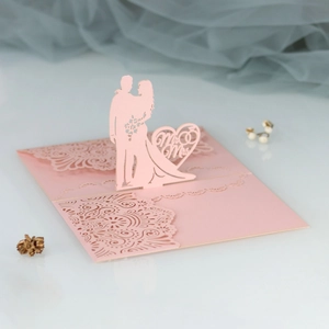 Close-up of pink laser-cut wedding invitation featuring Mr & Mrs 3D silhouette design