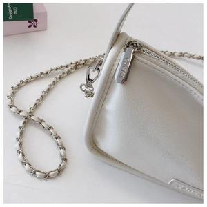 Close-up of white lychee textured leather handbag with silver zipper and chain strap